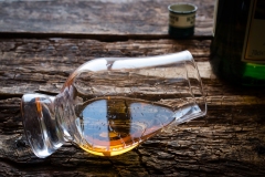 glass and bottle of whiskey on a wooden background